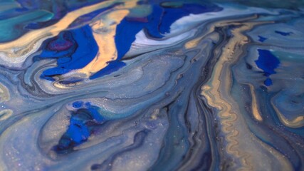 Blue, white, gray, black and shiny gold colors oil paint pouring. Fluid Art painting. Moving flowing stream of liquid paint. Decorative abstract background