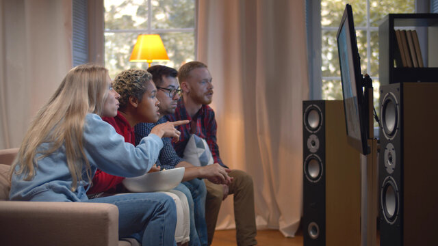 Side view of diverse friends with popcorn watching tv at home - Powered by Adobe