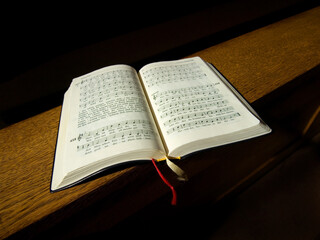 Gesangbuch liegt auf der Kirchenbank.