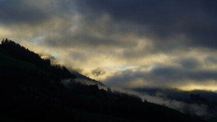 Obraz premium sunrise with dark clouds and sunlight over the mountains