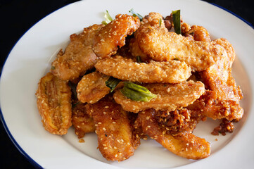Fried banana mix sesame and pandan leaf for aroma (Thai called Kluay Thod) in white dish and Banana on black cloth background Thai snack
