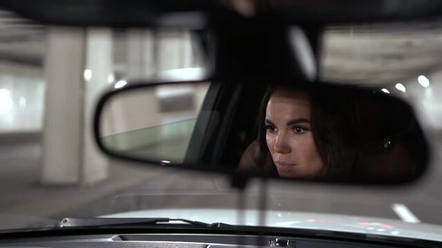 A young beautiful brunette girl, reflected in the windshield, is driving in a car, she is driving in a tunnel.