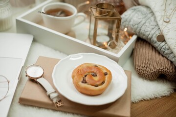 Breakfast. Laptop, mug of hot tea, bun, candle, eucalyptus in a vase. Cozy autumn. Home.