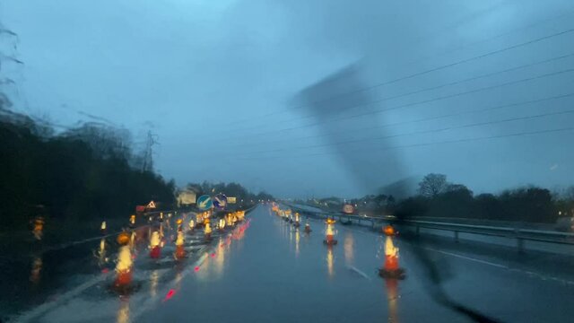 Driving through roadworks in heavy rain on a winter night. View through windscreen. 