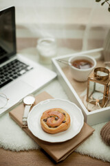 Breakfast. Laptop, mug of hot tea, bun, candle, eucalyptus in a vase. Cozy autumn. Home.