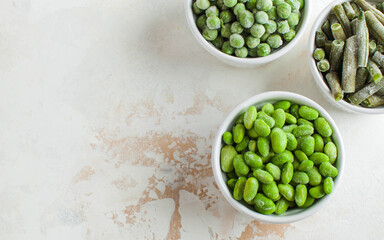 Frozen vegetables green peas, soy, green beans, and baby food in white bowls with copy space. Healthy food, frozen food