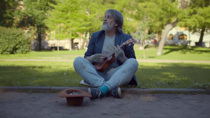 Homeless musician playing guitar and singing begging for money on street