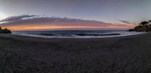 playa al amanecer de nerja con olas y nubes de fondo