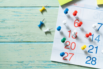 close up of calendar and pin on the green table background, planning for business meeting or travel planning concept