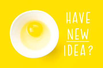 Raw egg in bowl and text Have New Idea on yellow background. Minimal creative idea concept for startup and business.