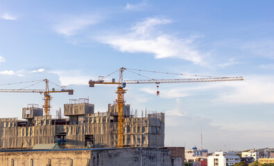 Fototapeta na wymiar A huge crane at hotel or condo building construction site with blue sky