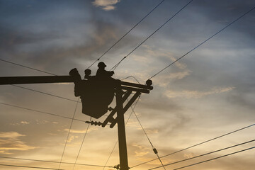 Silhouette engineer or electrician is working on a bucket. To repair high-voltage transmission...