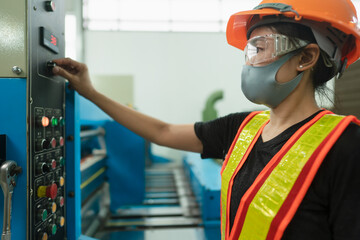 Professional Industrial worker operate heavy machine to setting a mechanic controller in factory atmosphere, Technician female engineer with safety wear and face mask in heavy industry workplace.
