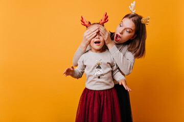 mom hid behind her daughter�s back and covers her eyes with her hands while her daughter tries to understand who it is