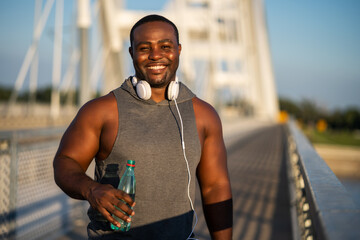 Portrait of young cheerful african-american man in sports clothing who is looking at camera and...