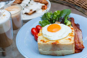 Ham and cheese sandwich with bechamel sauce and topped with a fried egg, known as Croque-madame. Croque madame sandwich on the table. Hot french toasts with ham, melted emmental cheese and fried egg.
