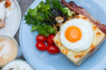 Ham and cheese sandwich with bechamel sauce and topped with a fried egg, known as Croque-madame. Croque madame sandwich on the table. Hot french toasts with ham, melted emmental cheese and fried egg.