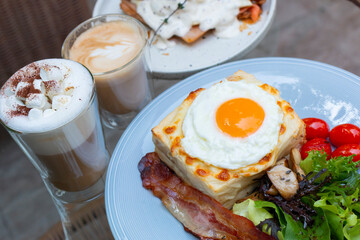 Ham and cheese sandwich with bechamel sauce and topped with a fried egg, known as Croque-madame. Croque madame sandwich on the table. Hot french toasts with ham, melted emmental cheese and fried egg.