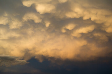 Clouds in the evening - yellow and orange sunset light lit cloud. Beautiful nature, landscape and cloudscape scenery. Very soft abstract style. Warm yellow and orange color.