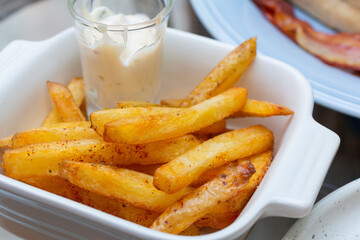 Crispy Potato French Fries in white bowl. French fries with dip sauce closeup on the table. Homemade Baked Potato Fries with Mayonnaise on white bowl. Close up Tasty Fried potato snacks in bowl.