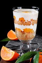 Trifle dessert with sponge cake crumbs, tangerine confit and custard served in the glass. English...