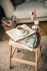 Toned photo. Autumn decor. A mug of hot tea, Knitted sweaters, book, glasses . Cozy. Autumn.