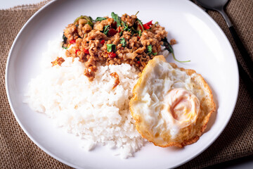 Pork basil with fried egg in a white plate on a white background.