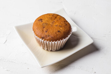 A cupcake in a ceramic plate on a white background