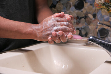 young man washing hands with soap warm water 