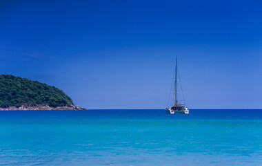 Snow-white  yacht catamaran stand in a picturesque bay surrounded by green hills 