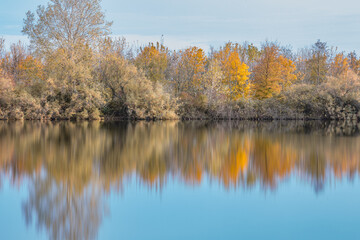 Fototapeta na wymiar Autumn forest landscape reflection on the waters of small lake at sunset lights of sun