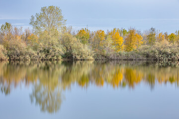 Autumn forest landscape reflection on the waters of small lake at sunset lights of sun