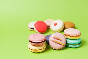 Light green background with macarons or macaroons in the foreground with blur. Side view, selective focus, copy space
