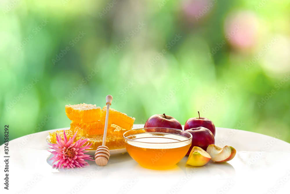 Wall mural Honey, red apples and flower on white table on the blur natural background with space for text