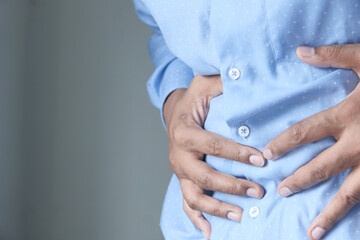 man touching stomach suffering pain close up.