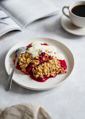 Plum crumble on white plate with coffee