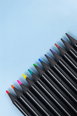 Multi-colored pencils on a blue background in a row