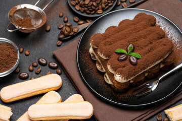 Classic tiramisu dessert and savoiardi cookies on ceramic plate on concrete background