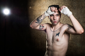 Obraz na płótnie Canvas Muai thai fighter posing in studio shot with tattoos