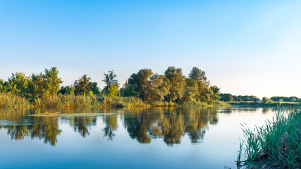 Obraz premium Scenery of silent rural lake near green forest.