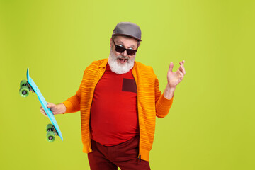 Skater man. Portrait of senior hipster man in fashionable eyewear isolated on green studio...