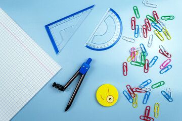 Multi-colored paper clips, rulers, notebook on a blue table