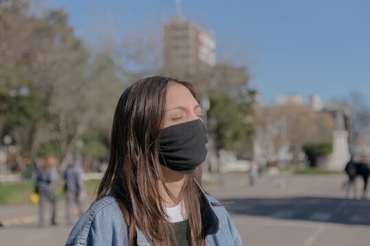 Mujer joven al sol con barbijo