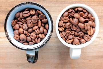 Cup of coffee beans on a wooden table. Close-up of coffee beans in ceramic cups on wood background with copy space. Rustic style
