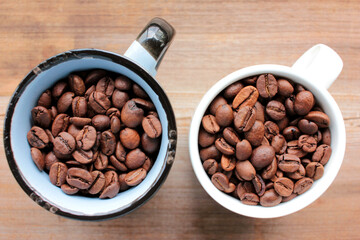 Cup of coffee beans on a wooden table. Close-up of coffee beans in ceramic cups on wood background...