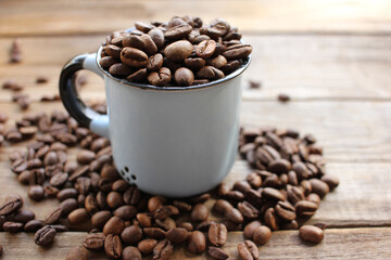 Cup of coffee beans on a wooden table. Close-up of coffee beans in a brown ceramic cup on wood background with copy space. Rustic style
