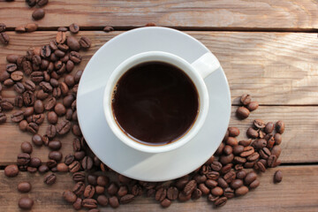 Cup of coffee with beans. Black coffee and scattered coffee beans on wooden table from above. Flat lay food composition