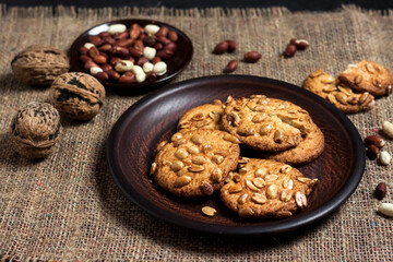 Homemade peanut cookies on a brown plate with raw peanuts in background