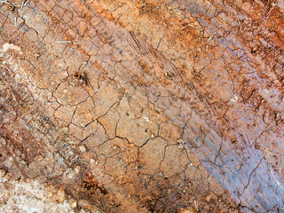 Traces of off-road tires. Cracked earth on country road with traces of tires, cars, cracks and dirt. To use as background.