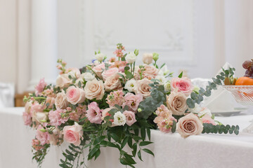 A beautiful floral arrangement in light colors is on the table with a white tablecloth.